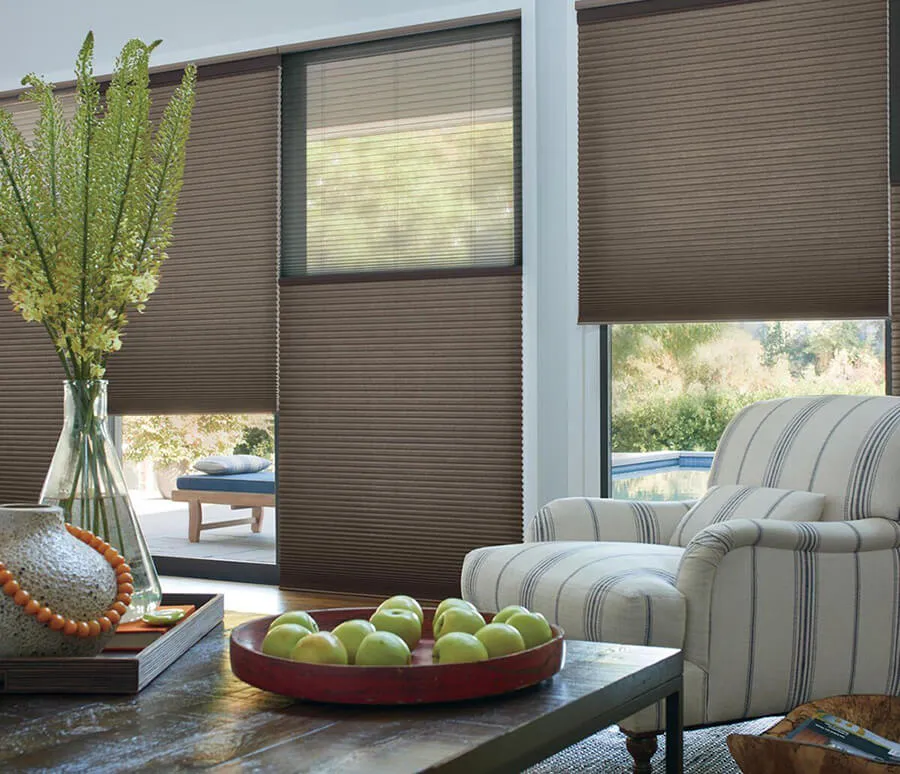 Stylish honeycomb shades in a sunny room with a striped armchair.