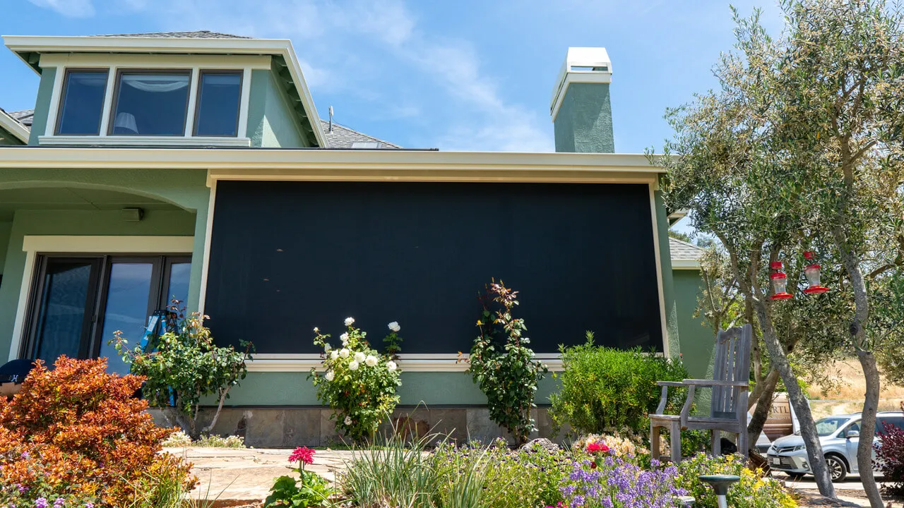 House with large black solar screen on patio.