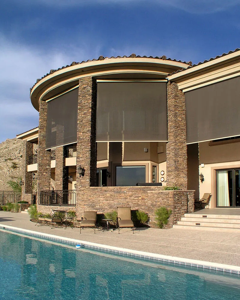 Large stone house with solar screens and pool.
