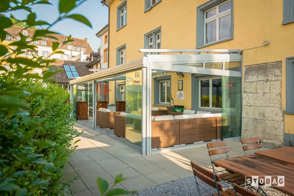Glass patio enclosure with wicker furniture.