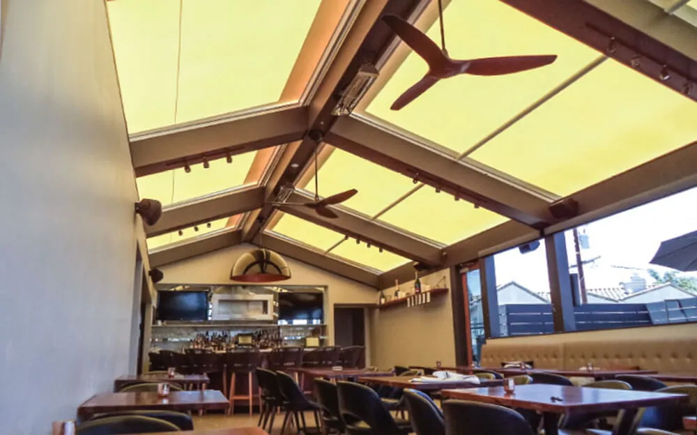 Sunny restaurant with skylight covers and ceiling fans.