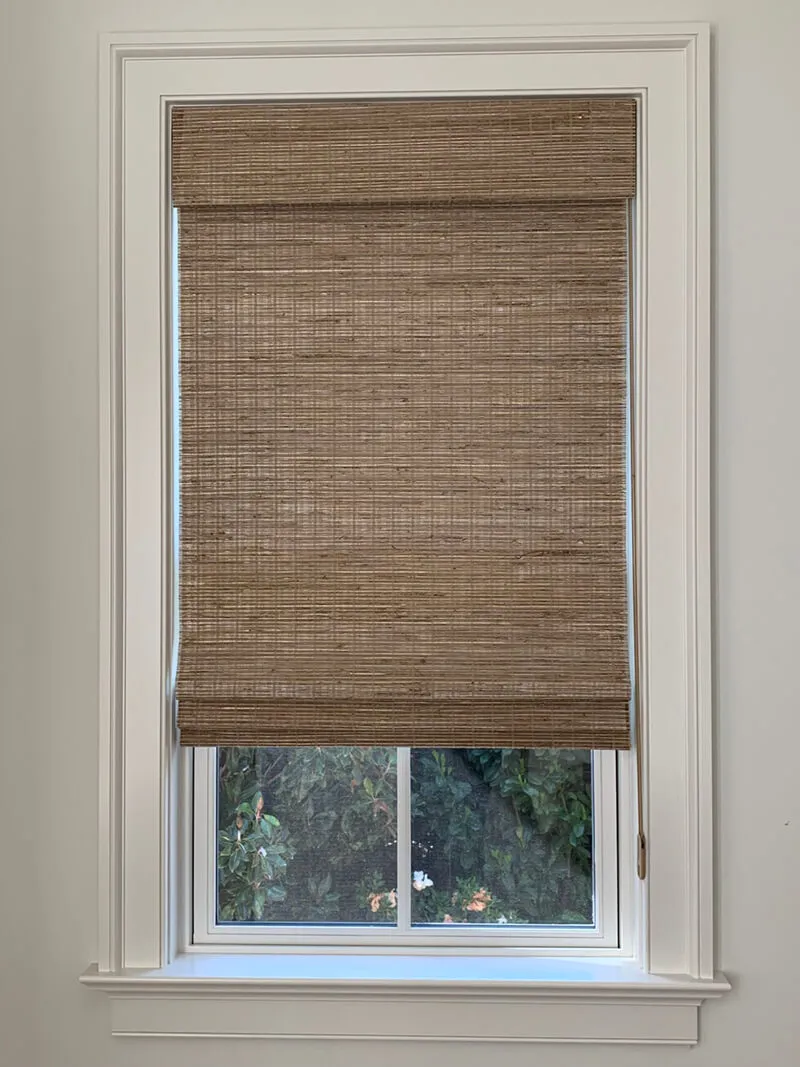 Woven wood shade on window with white trim.