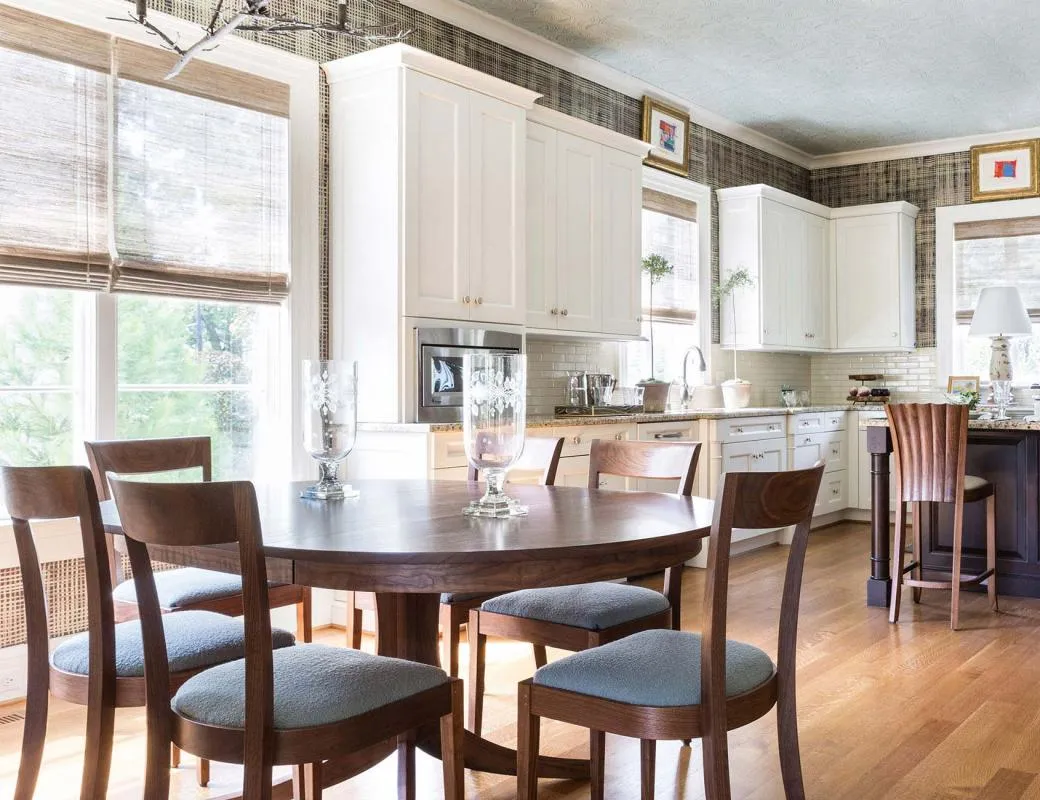 Light-filled kitchen with woven wood shades and wooden dining set.