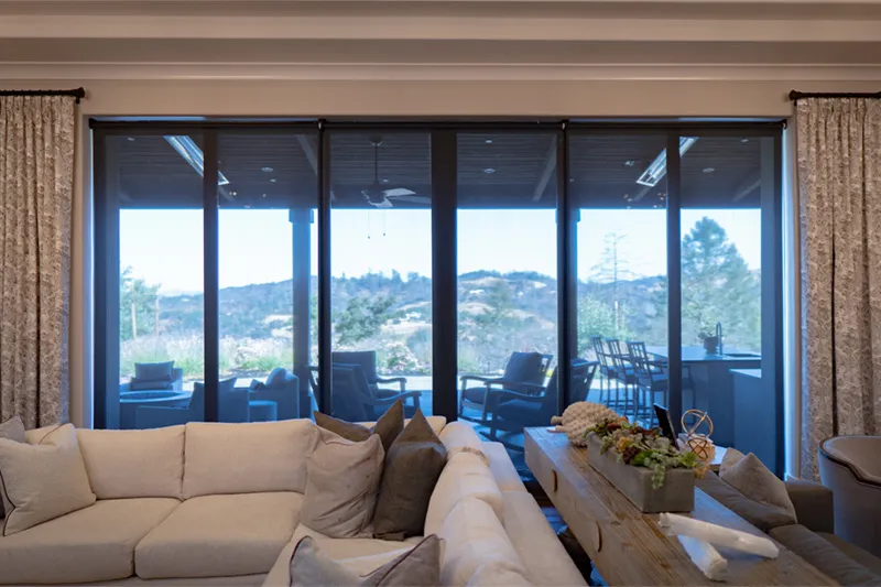 Sliding glass doors with shades, view of outdoor patio and landscape.