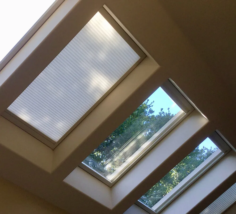 Three skylight windows with shades, two drawn closed.