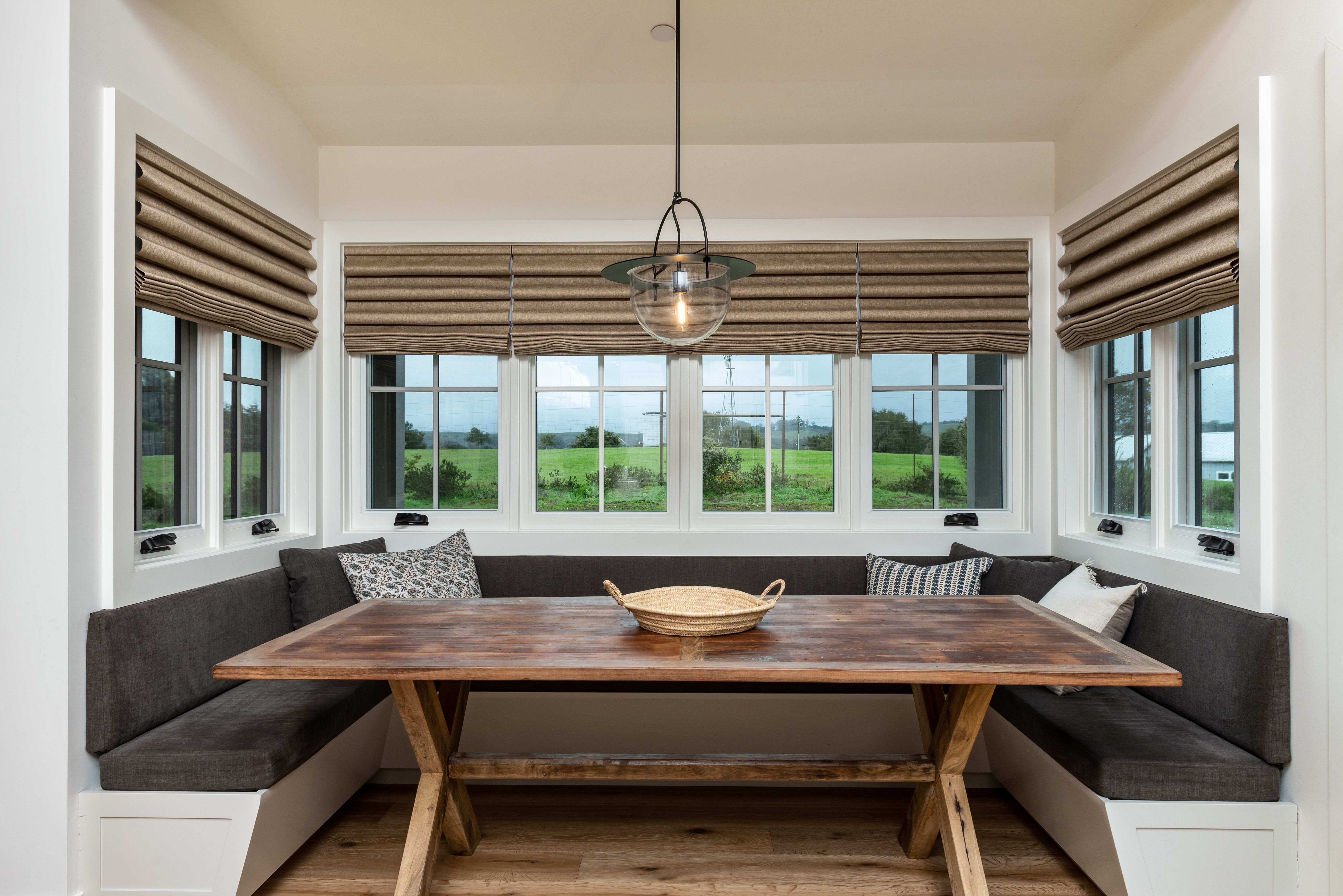 Dining nook with Roman shades and rustic table.