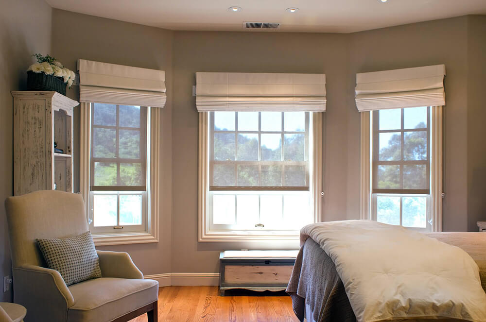 Bedroom with Roman shades on three windows.