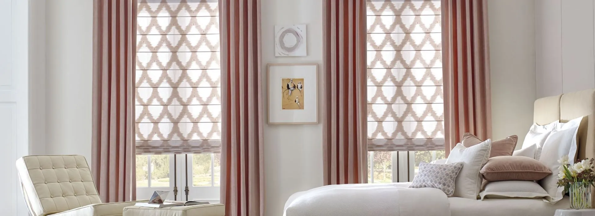 Bedroom with patterned Roman shades and pink curtains.