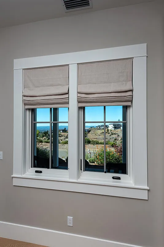 Roman shades on window with scenic view.