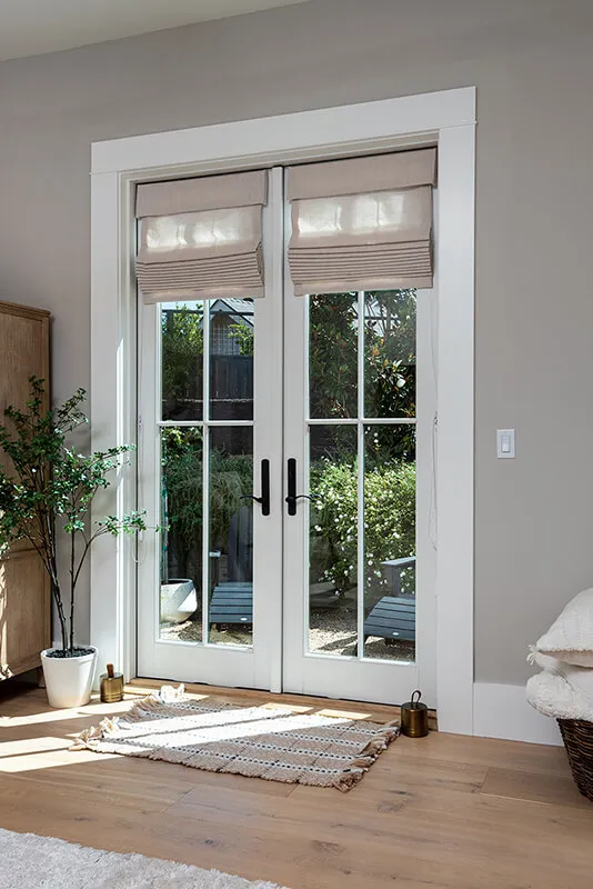 Roman shades on glass doors with black handles.