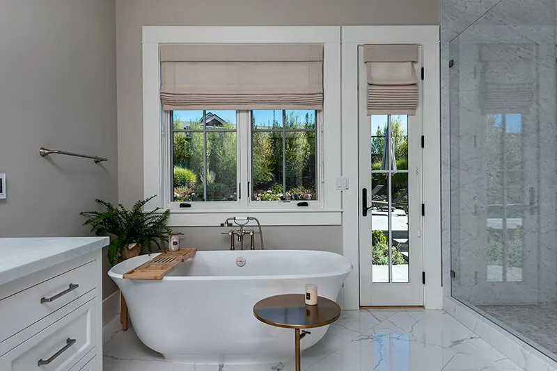 Bathroom with Roman shades, bathtub, and glass shower.