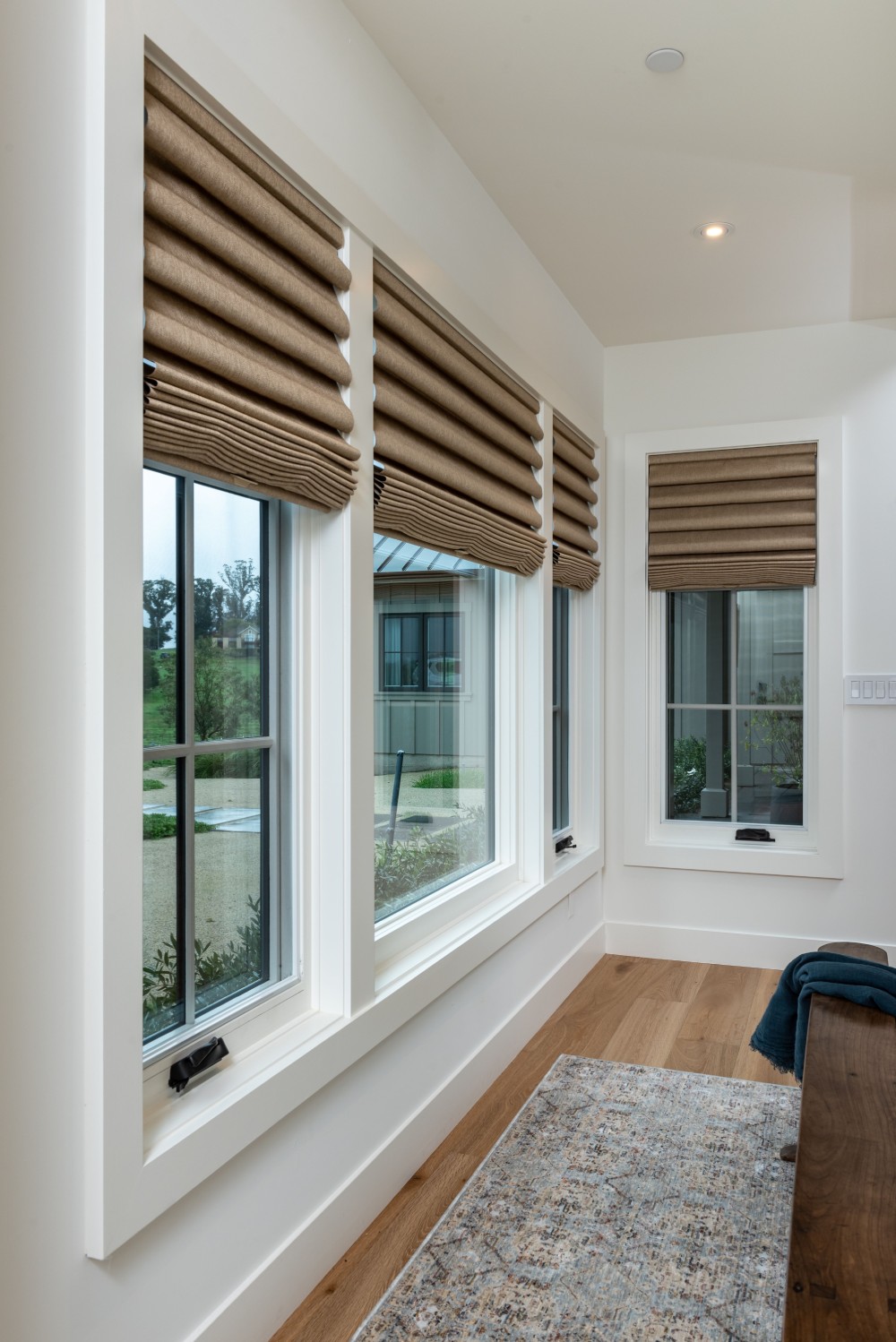 Three beige Roman shades on large windows.