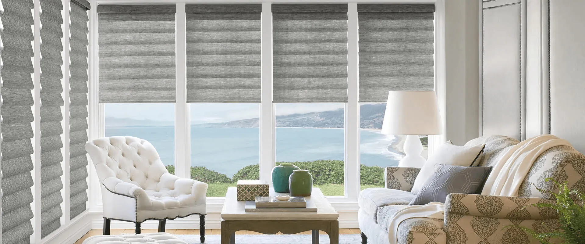 Living room with gray Roman shades, ocean view.