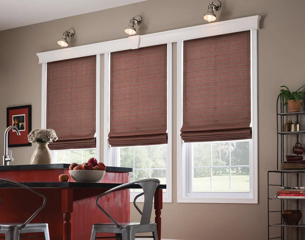Room with red Roman shades on three windows
