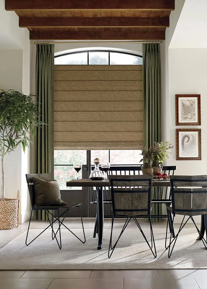 Dining room with Roman shades on large window.