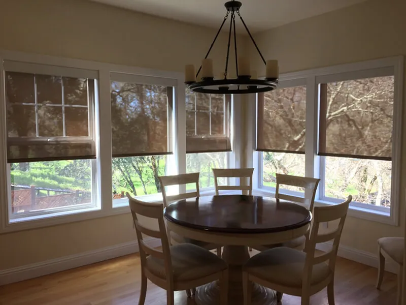 Dining area with roller shades.