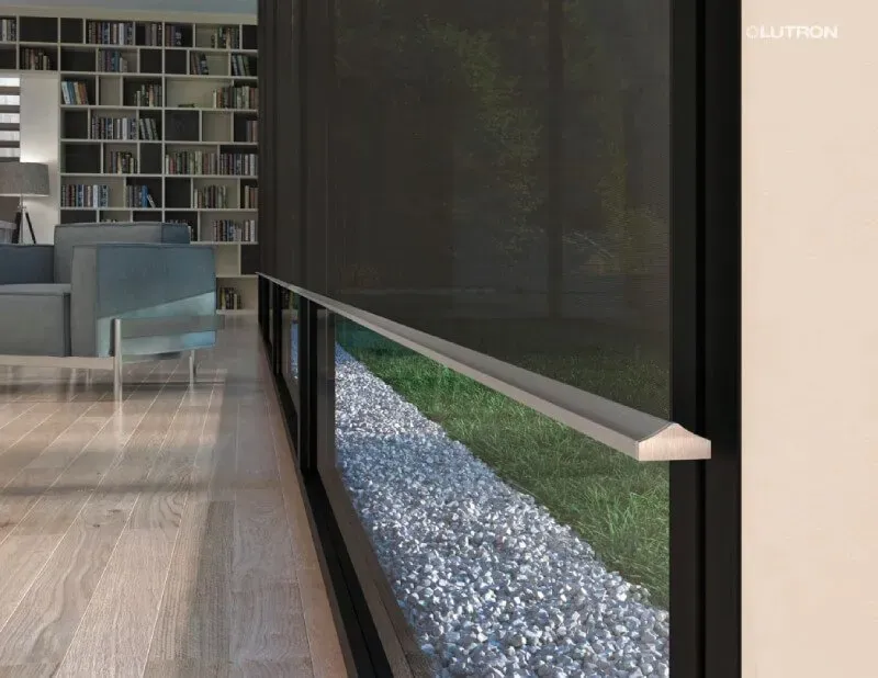 Modern living room with large windows, sheer blinds, wooden floors, and a cozy seating area by a bookshelf.