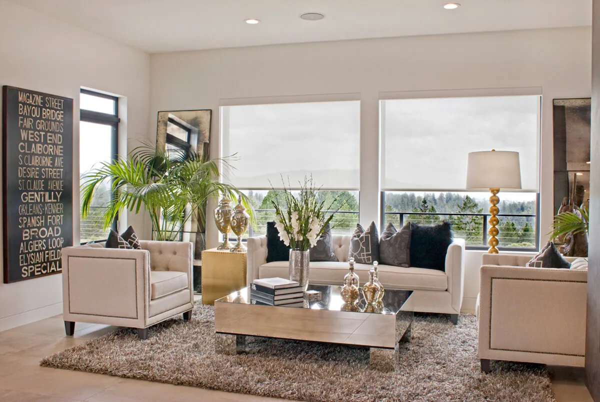Modern living room with beige sofas, large windows, decorative plants, and a plush rug.