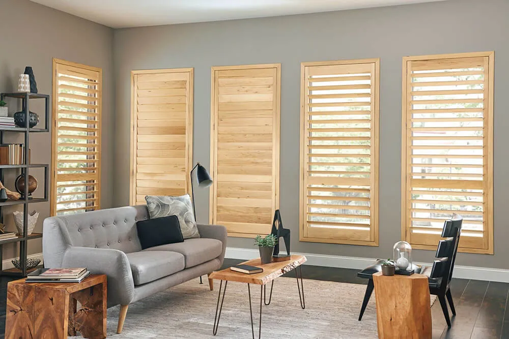 Classic wood shutters installed in a bright room with natural light filtering through the louvers.