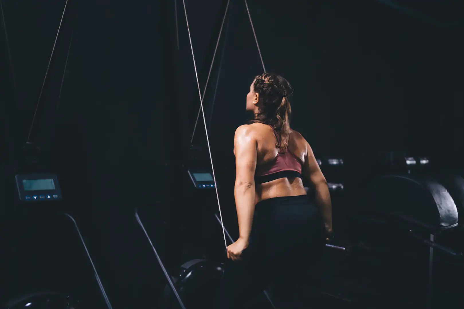 Athletic woman using a SkiErg ski ergometer machine, representing full-body conditioning, endurance cardio training, cross-training equipment, and gym fitness routines.