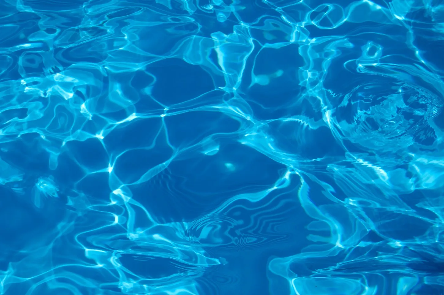 Clear blue water with sunlight creating ripples and patterns on the surface.