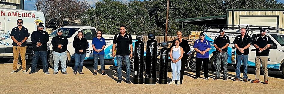 Jason's Water team standing outdoors in front of the branded vehicles.