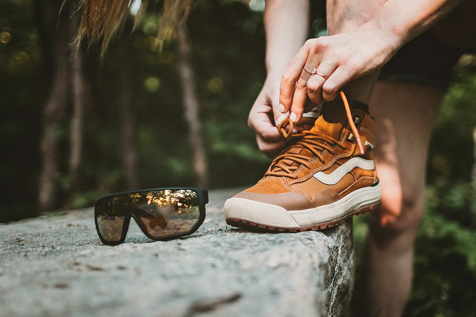 Sunglasses sitting next to a person tying shoes