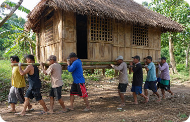Filipino community members carrying a traditional bahay kubo house together