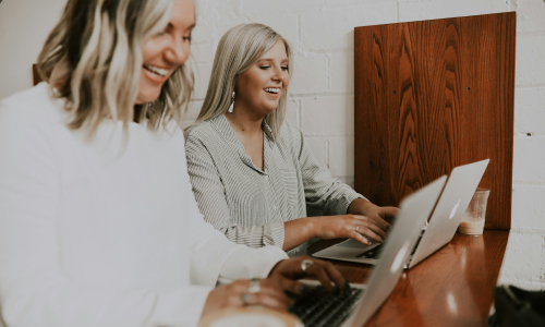 Two business women typing on laptop
