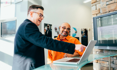 Business man pointing at laptop and talking to employee