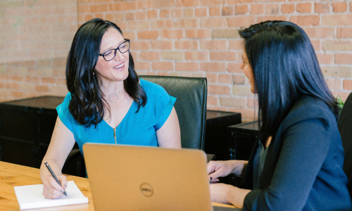 Two business women at laptop talking