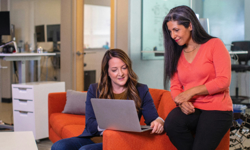 Two female co-workers sitting around laptop