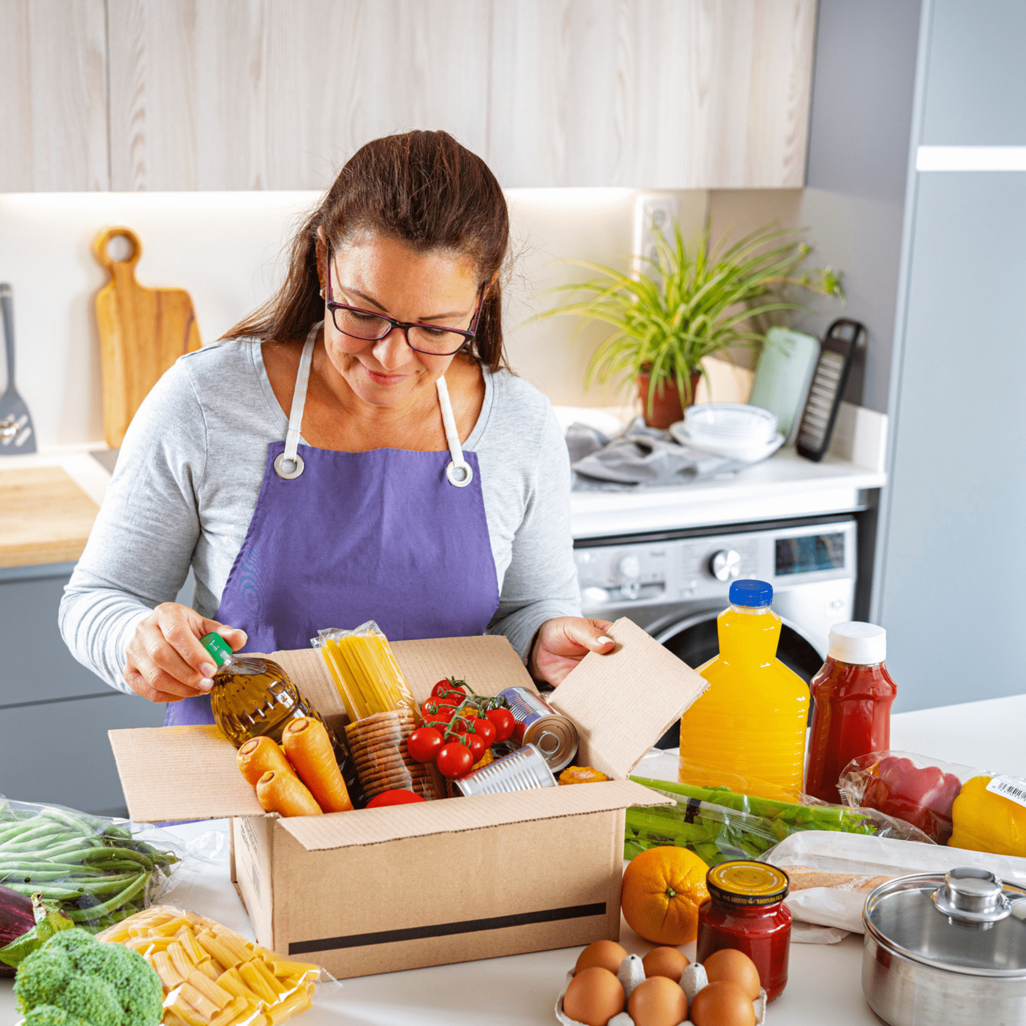 woman unboxing a food delivery of fresh produce and pantry staples