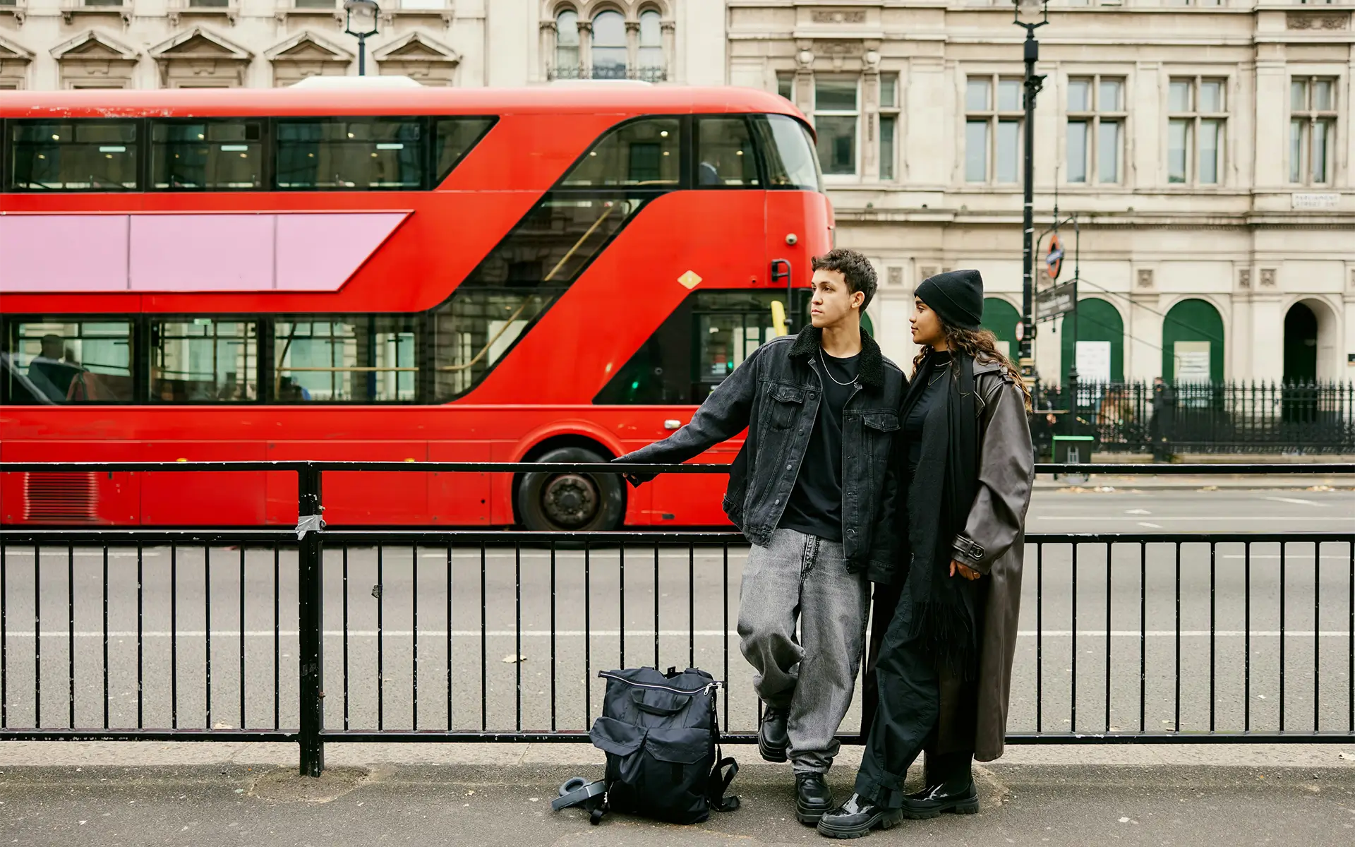 A young diverse couple stand in front of a London bus, representing social mobility