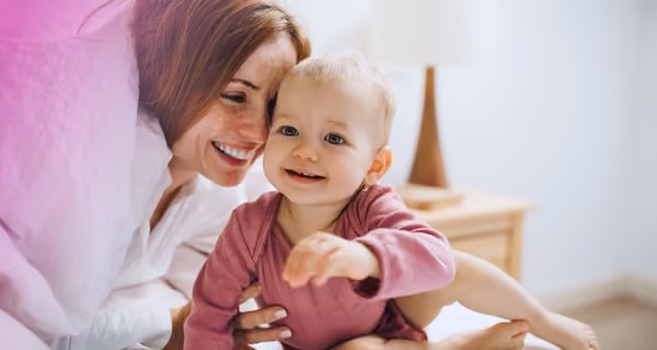 Smiling mother playing hide-and-seek with toddler