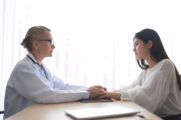 A fertility doctor talking compassionately with her patient in the clinic officee