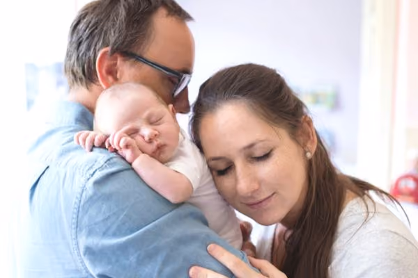 A couple embracing their newborn baby