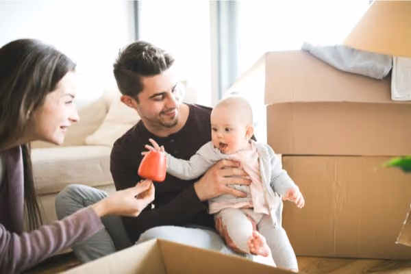 Young couple with baby in between boxes in their new home