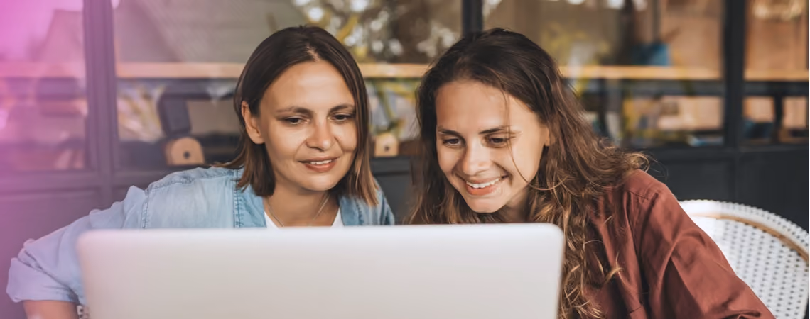 Smiling lesbian couple reading about fertility treatment on their computer
