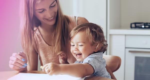 Young mother helps her child with cartoons on the kitchen table
