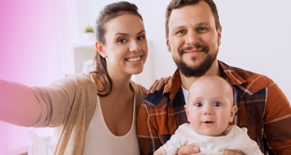 Smiling mother and father take selfie with their baby