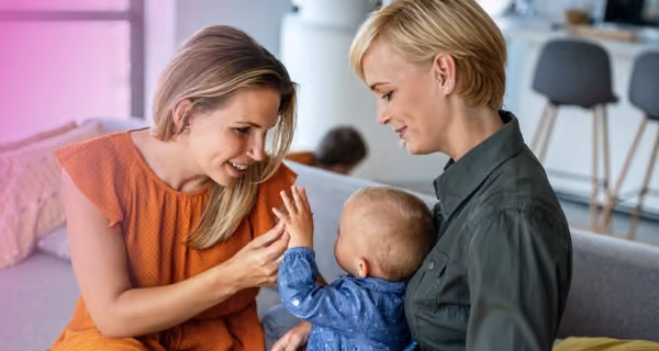 Lesbian couple playing with their child in the living room