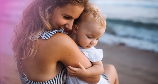Young mother on the beach giving her child a good hug