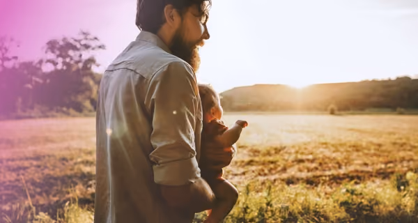 Young father carries his child across the field