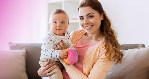 Young mother posing on sofa with her new child