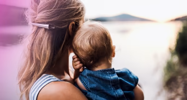 Young mother with child on her arm looking out at the horizon