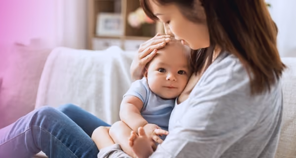 Young mother lovingly holds her child in the corner of the sofa