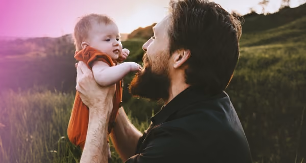 A happy father in scenic surroundings lifts up his child