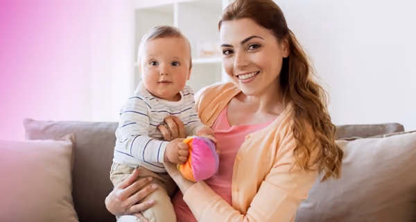 Young mother posing on sofa with her new child