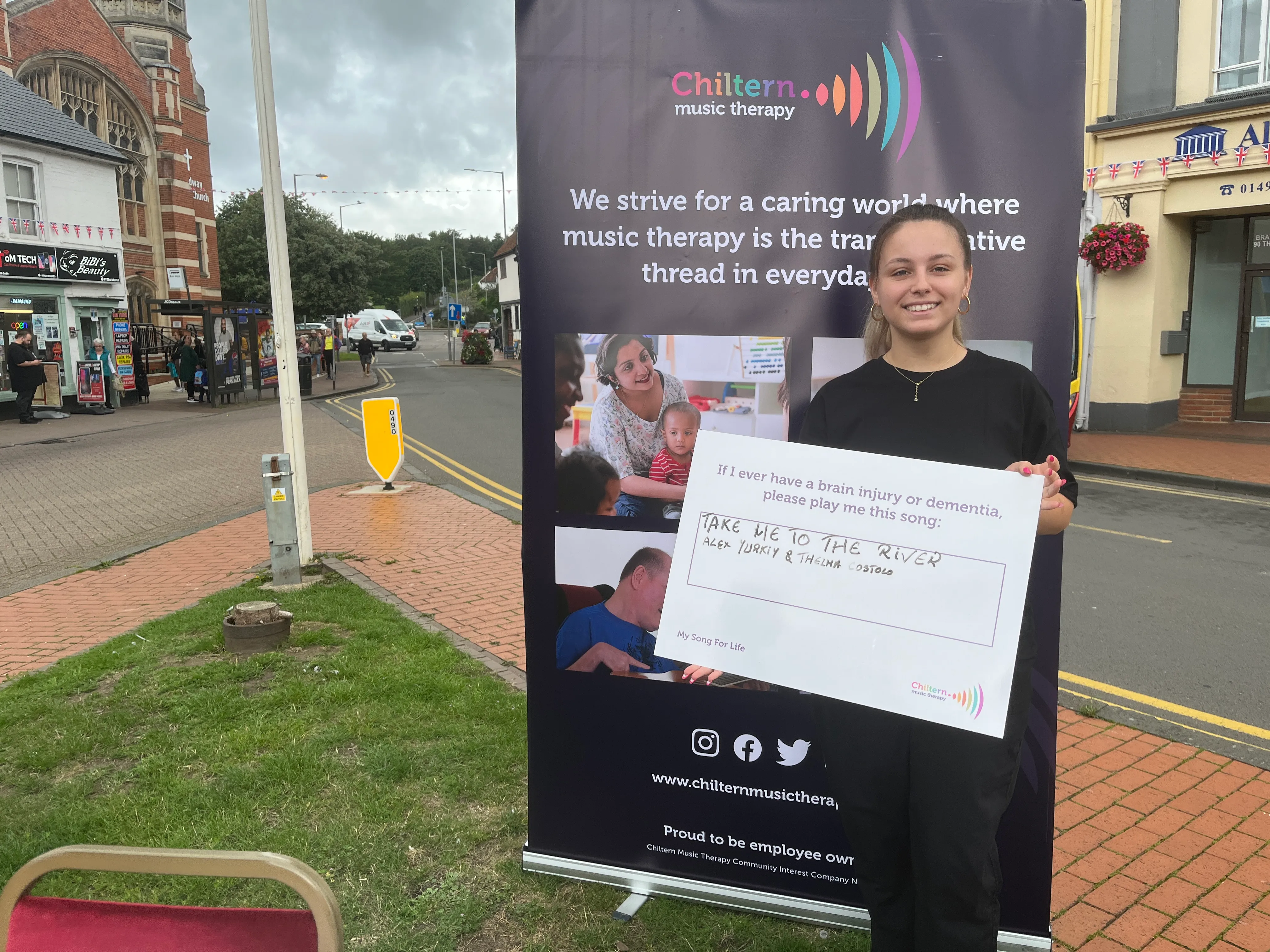 Image is of a women holding a sign that says "If I ever have a brain injury or dementia, please play me this song", underneath in handwriting it says "Take me to the river - Alex Yurkiy & Thelma Costolo""